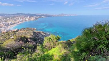 Güneşli, mavi gökyüzünün altında nefes kesici kıyı şeridi ve kristal berrak suların nefes kesici manzarasını tecrübe edin.