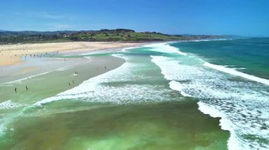 İnanılmaz berrak suları ve dalgalı dalgalarıyla nefes kesici bir sahili gösteren hava manzarası.