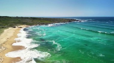 Bu sakin sahil sahnesinde turkuaz suların yumuşak kumlu kıyılarla harmanlanmasının güzelliğini hissedin..