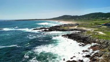 Açık gökyüzünün altındaki kayalık kıyılara çarpan dalgalarla sahilin nefes kesici güzelliğini yakalayın.