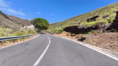 Güzel, dolambaçlı bir yol görkemli dağların arasından geçer, yemyeşil ve açık mavi gökyüzü