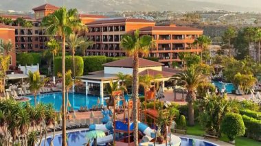 Birden fazla havuz ve palmiye ağaçlarıyla çevrili heyecan verici su kaydıraklarının olduğu çarpıcı lüks bir otel..