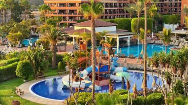 Muhteşem havuzları, heyecan verici slaytları ve güzel yeşillikleri olan lüks bir tatil köyünün çarpıcı manzarasının tadını çıkarın.