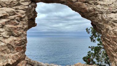 Kayalık bir kemer tarafından çerçevelenmiş büyüleyici kıyı manzarasının tadını çıkarın, doğa severler ve seyahat meraklıları için ideal.