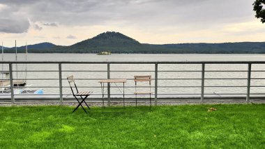 Davetkar ve rahatlatıcı bir göl manzarası, geniş bir masa ve konforlu sandalyelerin yer aldığı