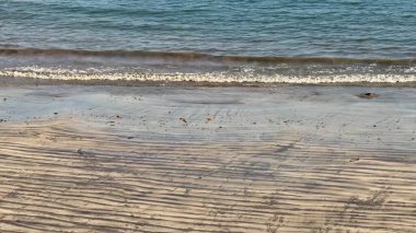 Sakin bir sahil sahnesi, yumuşak dalgaların altın kumlu sahillere vurduğu, tam bir rahatlama ve gevşeme için ideal.