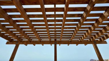 Güzel bir ahşap pergola tam rahatlama için mükemmel, dingin bir okyanus zeminiyle geniş bir gölge sağlar.