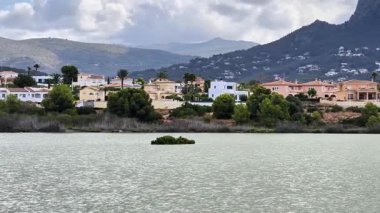 Huzurlu ve pitoresk göl manzarası. Konforlu evler, canlı yemyeşil yerler ve etrafını saran görkemli dağlar.