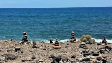 Parlayan suyla istiflenmiş dengeli taşların sakin manzarası, sakin bir sahil ortamı yaratıyor.