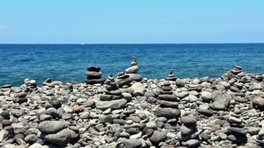 Huzurlu ve sakin bir manzara sergilenen taşlar okyanus dalgalarının yanındaki kayalık bir sahilde güzelce yerleştirilmiş.