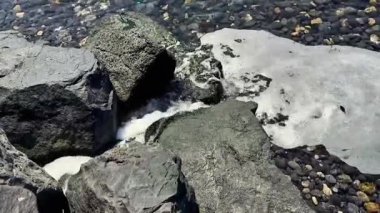 Deniz kayalık kıyı boyunca akar, beyaz köpük yaratır ve doğal güzellikleri yakalar.