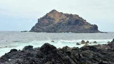 Okyanus dalgalarıyla çevrili kayalık bir adanın çarpıcı manzarası doğa severler ve macera arayanlar için mükemmel.