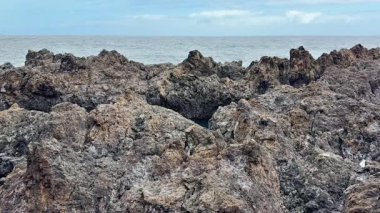 Okyanus boyunca uzanan nefes kesen doğal dokuları ve kıyı güzelliğini gösteren çarpıcı kayalık bir kıyı şeridi.