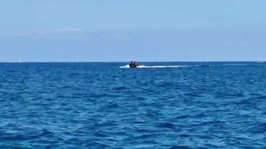 Heyecan verici bir sürat teknesi, berrak bir gökyüzünün altındaki büyüleyici güzellikteki gök mavisi sularda hızla süzülüyor.