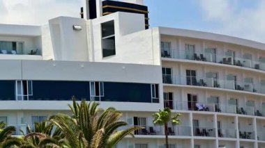 Modern otel tasarımı okyanus manzaralı güzel balkonlar ve palmiye ağaçları sergiliyor.