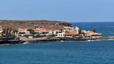 Tepeler ve deniz arasında kurulu büyüleyici bir sahil köyü manzarası, saf sükuneti sergiliyor.