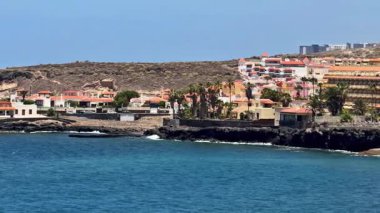 Engebeli kayalıkların yanında deniz kenarındaki canlı evleri gösteren nefes kesici bir kıyı manzarası.