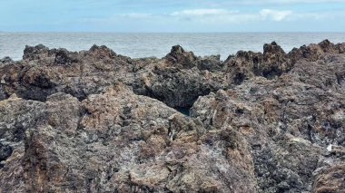 Okyanus boyunca uzanan nefes kesen doğal dokuları ve kıyı güzelliğini gösteren çarpıcı kayalık bir kıyı şeridi.