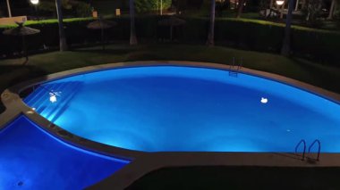 Geceleri, yemyeşil ve yumuşak ortam aydınlatmalarıyla çevrili huzurlu ve güzel aydınlatılmış bir havuz.