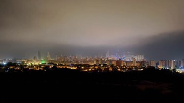 Geceleri gökyüzüne bakan büyüleyici bir manzara, canlı ışıklarla aydınlatılmış ve bulutlarla örtülmüş..