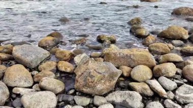 Huzurlu bir manzara, kayaları sergiliyor. Yumuşak dalgalarla onları sarmalıyor.