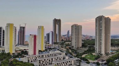 Modern gökdelenlerin çarpıcı bir görüntüsü canlı bir günbatımı arkaplanı karşısında, göz alıcı renkler sergiliyor.