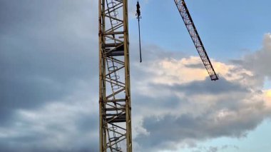 Bulutlu gökyüzüne karşı devasa bir vinç kulesi modern mühendislik ve kentsel gelişim sergiliyor.