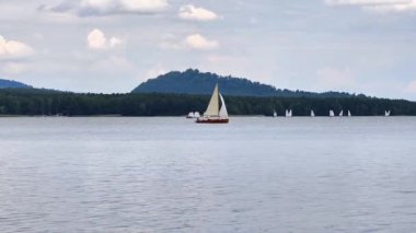 Yelkenliler bulutlu bir gökyüzünün altında sakin sularda süzülerek nefes kesici bir sahne hazırlıyorlar.