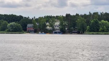 Canlı yemyeşil ve sakin bir su yüzeyinin ortasında yuva yapmış güzel göl kenarı evlerinin huzurlu ve resimsel manzarası.