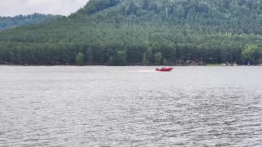 Güzel tepelerle çevrili sakin sularda yüzen şık bir sürat teknesinin manzarası.