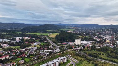 Bulutlu gökyüzünün altındaki kentsel alanların yanındaki yuvarlanan tepeleri gösteren güzel ve büyüleyici bir manzara.
