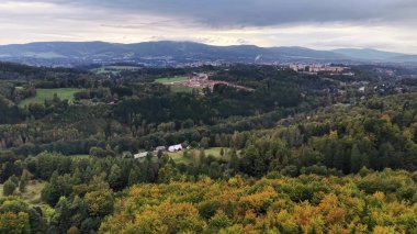 Güzel bir panoramik manzara bulutlu bir gökyüzüne karşı tepelik arazide canlı ve renkli sonbahar renklerini yakalıyor.