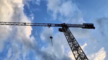 Bir inşaat vinci canlı bir gökyüzünün altında zarif bir şekilde duruyor ve şehir ortamlarındaki hayati rolünü gözler önüne seriyor.