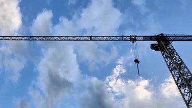 Bir inşaat vinci, güzel ve büyüleyici bulutlu gökyüzüne karşı çeşitli malzemeleri ustalıkla havaya kaldırır.