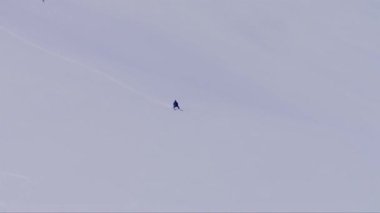 Karlı bir dağda kayak yaparken ters giden bir adamın havadan çekilmiş videosu.