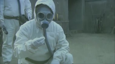 Koruyucu kıyafet ve gaz maskesi takan personelin videosu.