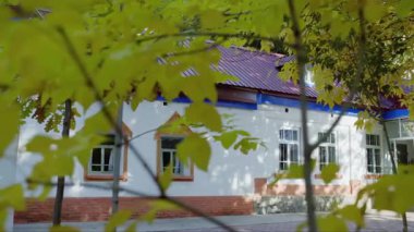 Avludaki dal ve yaprakların arasından Xinjiang 'ın karakteristik bungalovunun videosunu görmek için