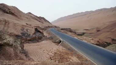 Dağlardan aşağı siyah bir araba iniyor, kavrulmuş topraklar, video