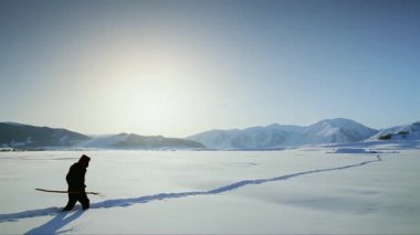 Bir adam derin karlar içinde çiğnenmiş bir yolda yürüyor.