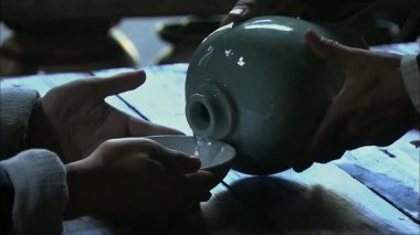 Adamın biri likör kavanozundan iki kase likör döktü.