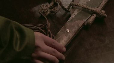 Yeşil üniformalı bir adam sağ koluyla kılıcına dokunuyor.