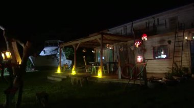 Geceleri deniz kenarında küçük ahşap bir ev, ahşap evin yanında beyaz bir yolcu gemisi.