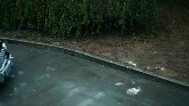 Plakası 0954 olan klasik siyah bir araba ıslak bir yolda sürüyor.