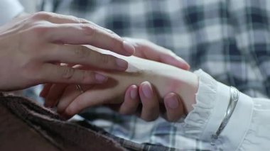 Bir adam yaralı bir kadının eline dokunuyor.