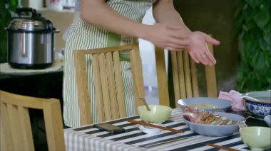 Bir adam elinde birkaç tabakla bir masada telefonunu kontrol ediyor.