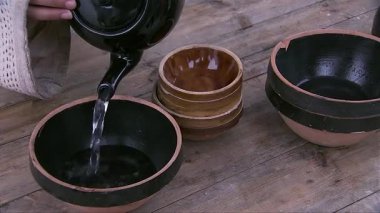 Bir kaseye su doldurmak için su ısıtıcısını kullanan başka bir kişi, el hareketlerini yakın plan olarak kaseyi tutar.