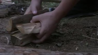 Kesilmiş odunları düzenlemek, bir parça odun toplamak ve bir adamın ellerini kesmeye hazırlanmak.