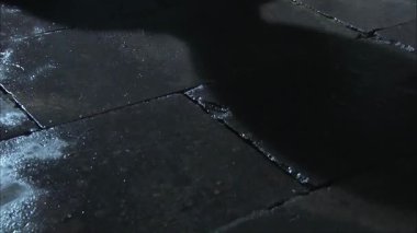 Beyaz deri ayakkabılı bir adam kaygan zeminde yürür, bacaklarını yakın çekimde.