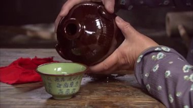 Şarap şişesinden şarap bardağına şarap dökmek, yaşlı bir kadının ellerine yakın çekim yapmak.