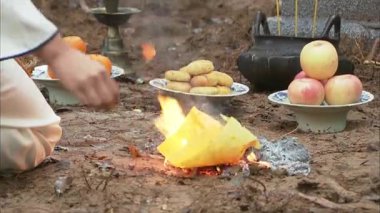 Mezarın önünde adaklar ve kağıt bağışları var. Mezar taşındaki Çince karakterler 